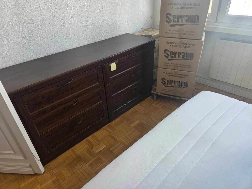 Cómoda y cajas de Mudanzas Serrano junto a una cama