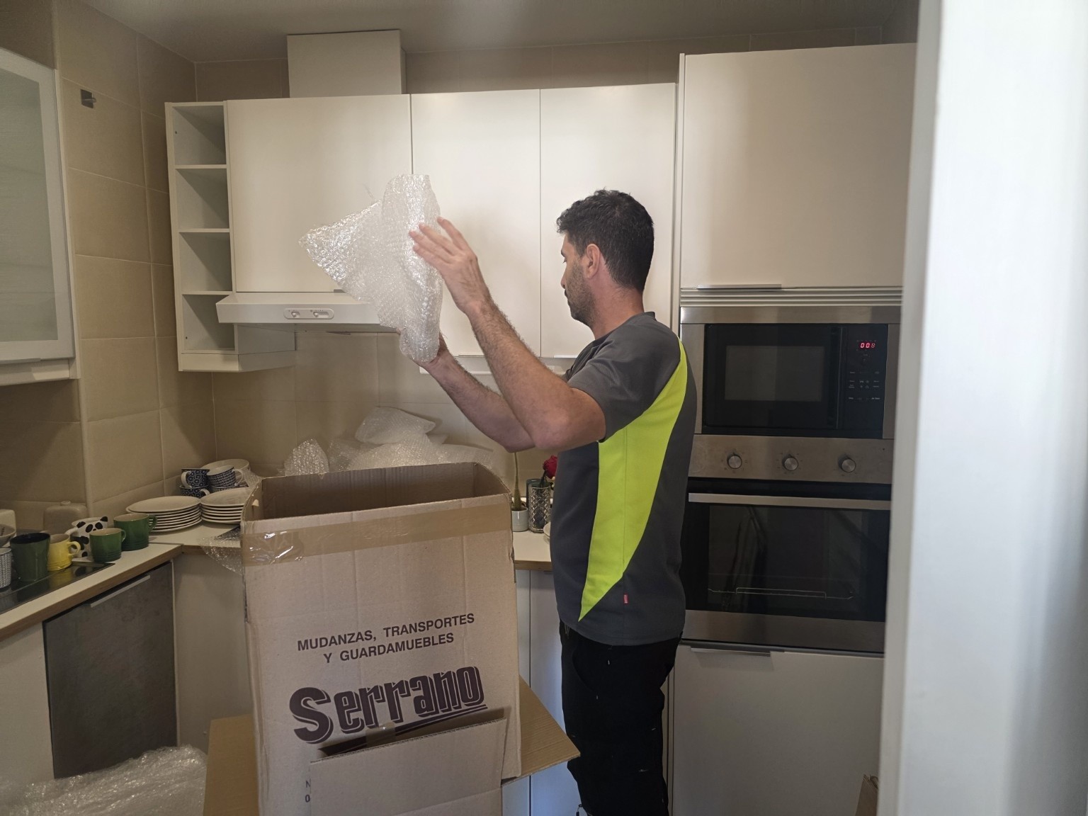 Operario preparando menaje de cocina con plástico de burbujas junto a una caja de Serrano